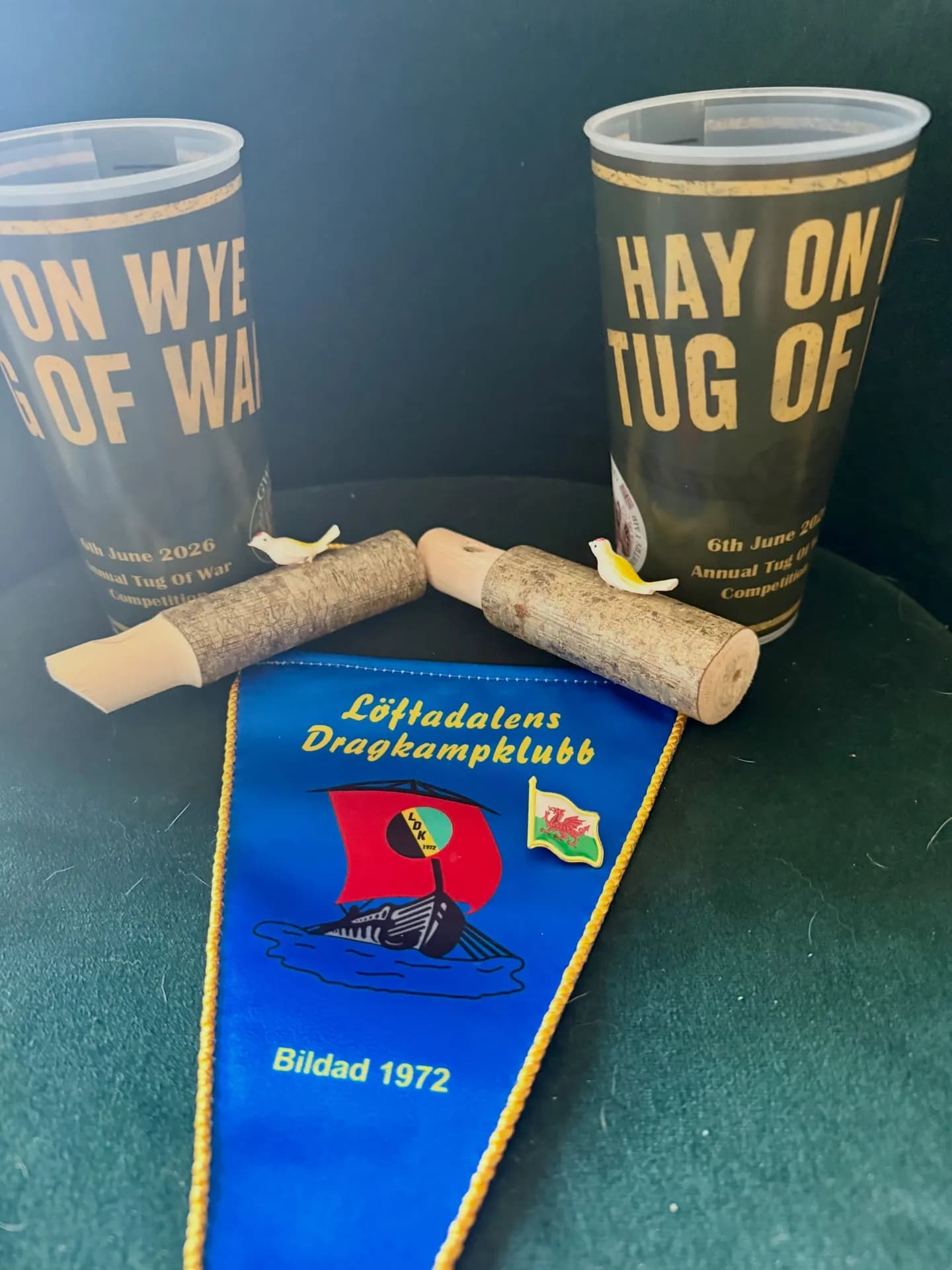 Souvenirs von anderen Vereinen: ein Wimpel von Löftadalens Dragkampklubb und Becher aus Hay-on-Wye. Tauziehen verbindet.